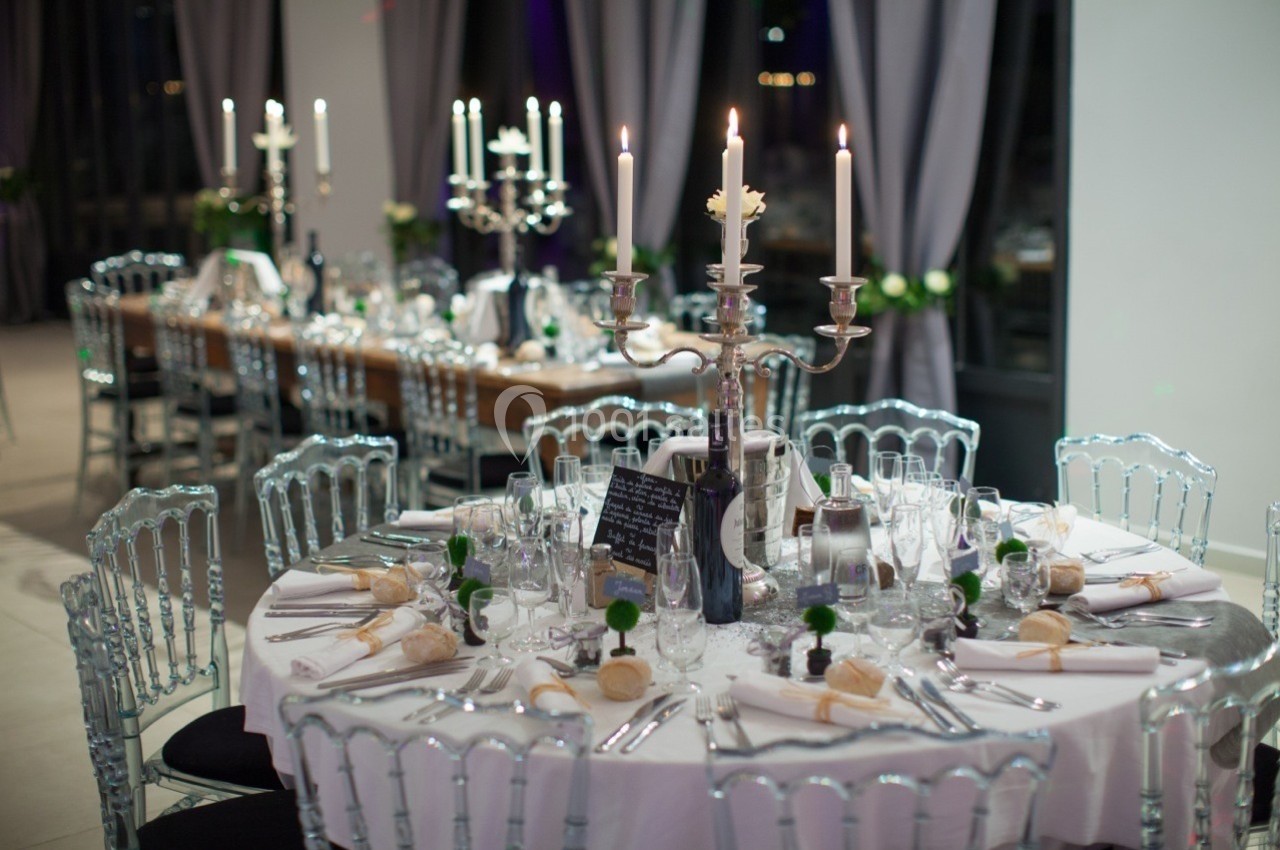 Table élégamment dressée avec chandeliers, vaisselle raffinée et décoration florale dans une salle de réception.