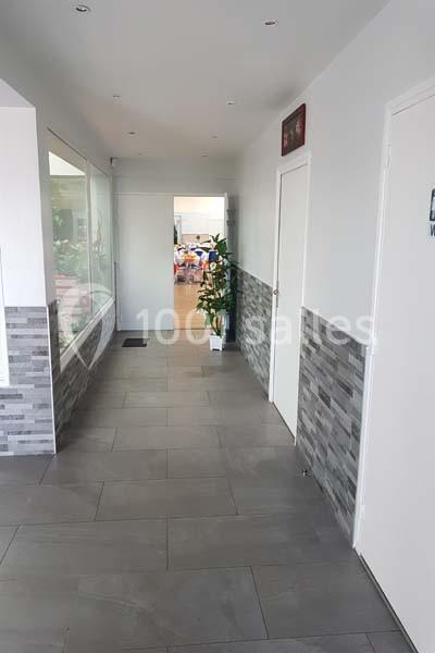 Location salle Nanteuil-lès-Meaux (Seine-et-Marne) - Centre D #25 Couloir lumineux avec carrelage gris, murs clairs, plantes décoratives et vue sur une salle en arrière-plan.