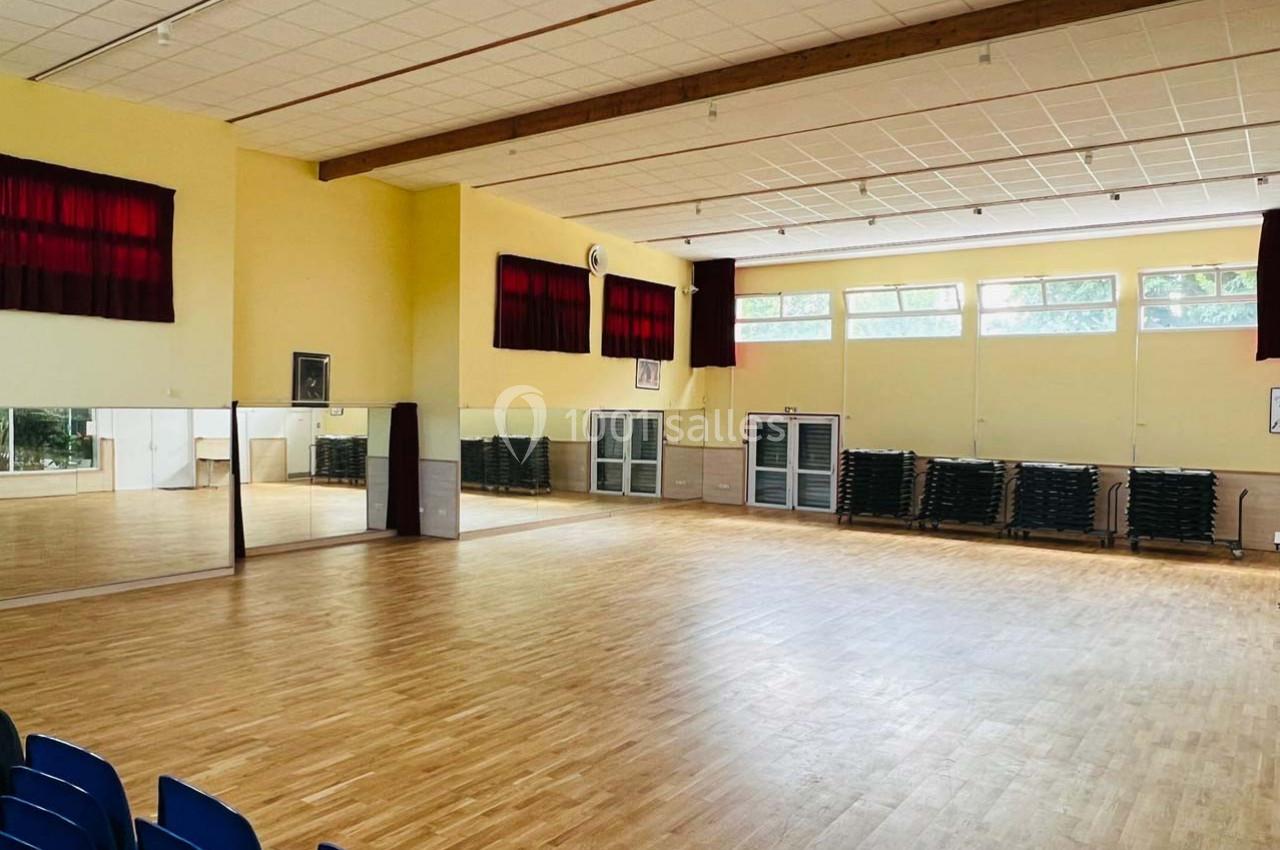 Location salle Nanteuil-lès-Meaux (Seine-et-Marne) - Centre D #19 Salle spacieuse avec parquet, miroirs sur un mur, fenêtres laissant entrer la lumière et chaises empilées au fond.