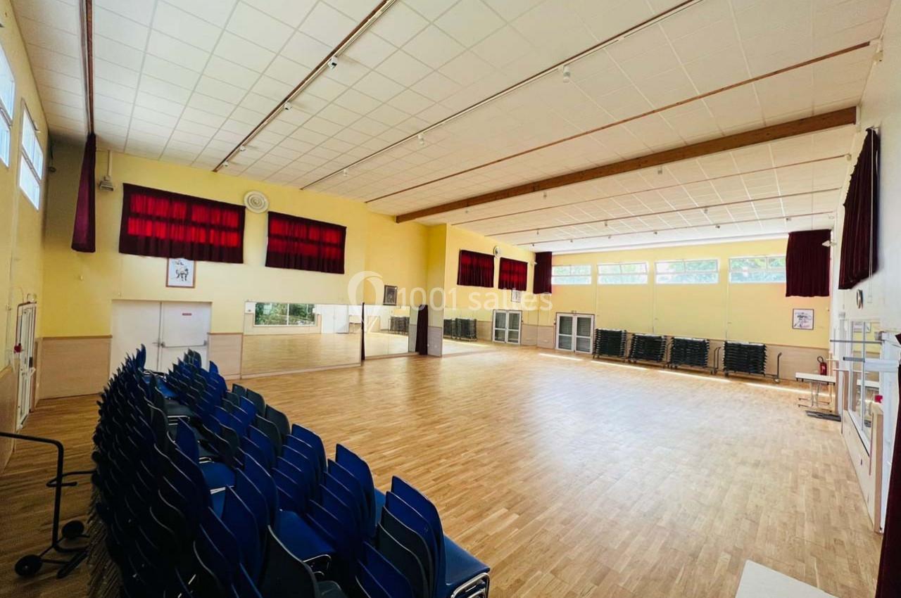 Location salle Nanteuil-lès-Meaux (Seine-et-Marne) - Centre D #17 Salle polyvalente lumineuse avec parquet, chaises empilées sur le côté et grandes fenêtres laissant entrer la lumière…