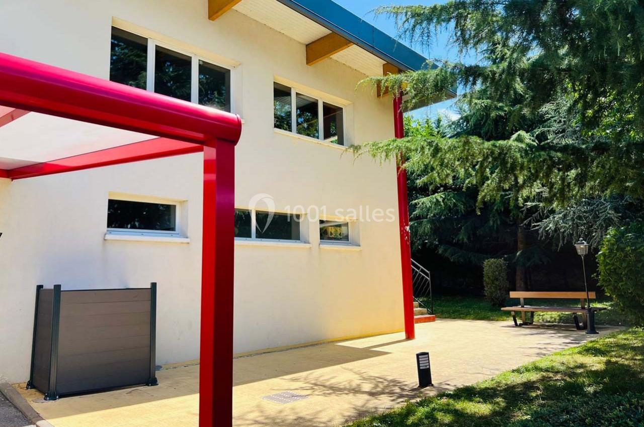 Location salle Nanteuil-lès-Meaux (Seine-et-Marne) - Centre D #29 Façade d'un bâtiment moderne avec des fenêtres, un auvent rouge et un espace extérieur arboré avec banc.