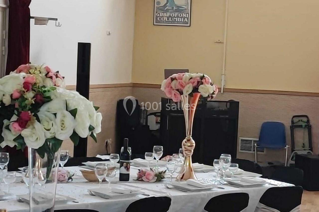 Location salle Nanteuil-lès-Meaux (Seine-et-Marne) - Centre D #8 Table dressée pour un événement avec nappes blanches, verres, assiettes et bouquets de fleurs en centre de table.