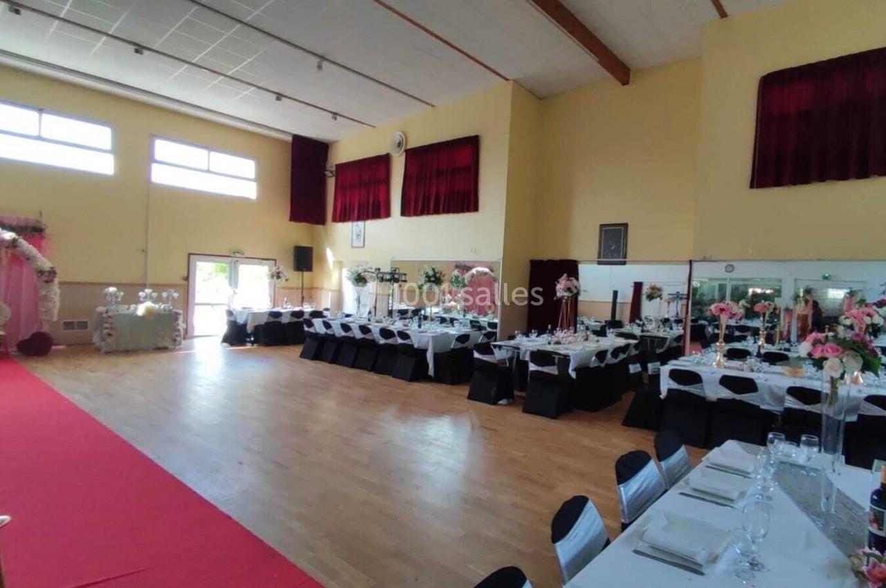 Location salle Nanteuil-lès-Meaux (Seine-et-Marne) - Centre D #5 Salle de réception décorée pour un événement, avec tables dressées, chaises noires et blanches, et fleurs roses.
