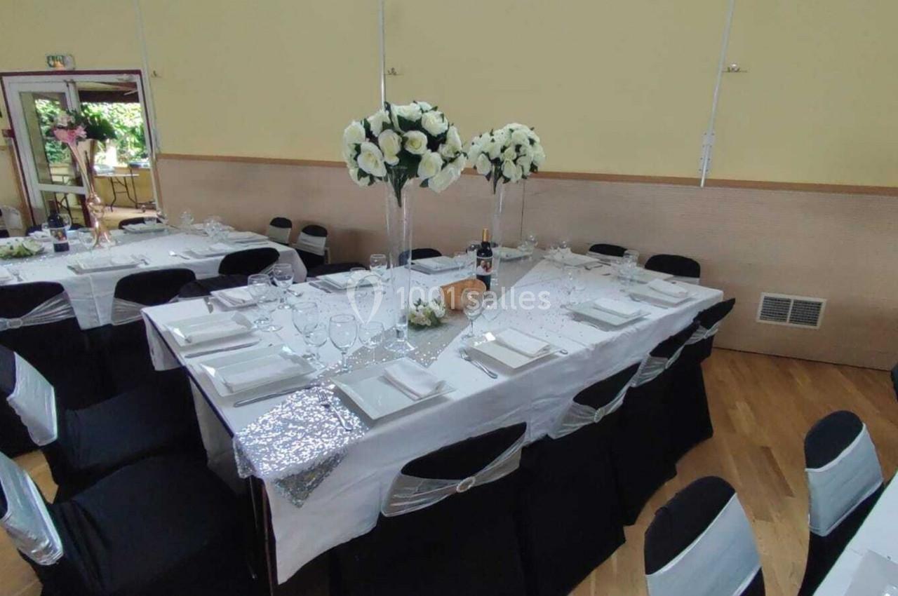 Location salle Nanteuil-lès-Meaux (Seine-et-Marne) - Centre D #6 Table de réception décorée avec nappes blanches, chaises noires, centres de table fleuris et vaisselle élégante.