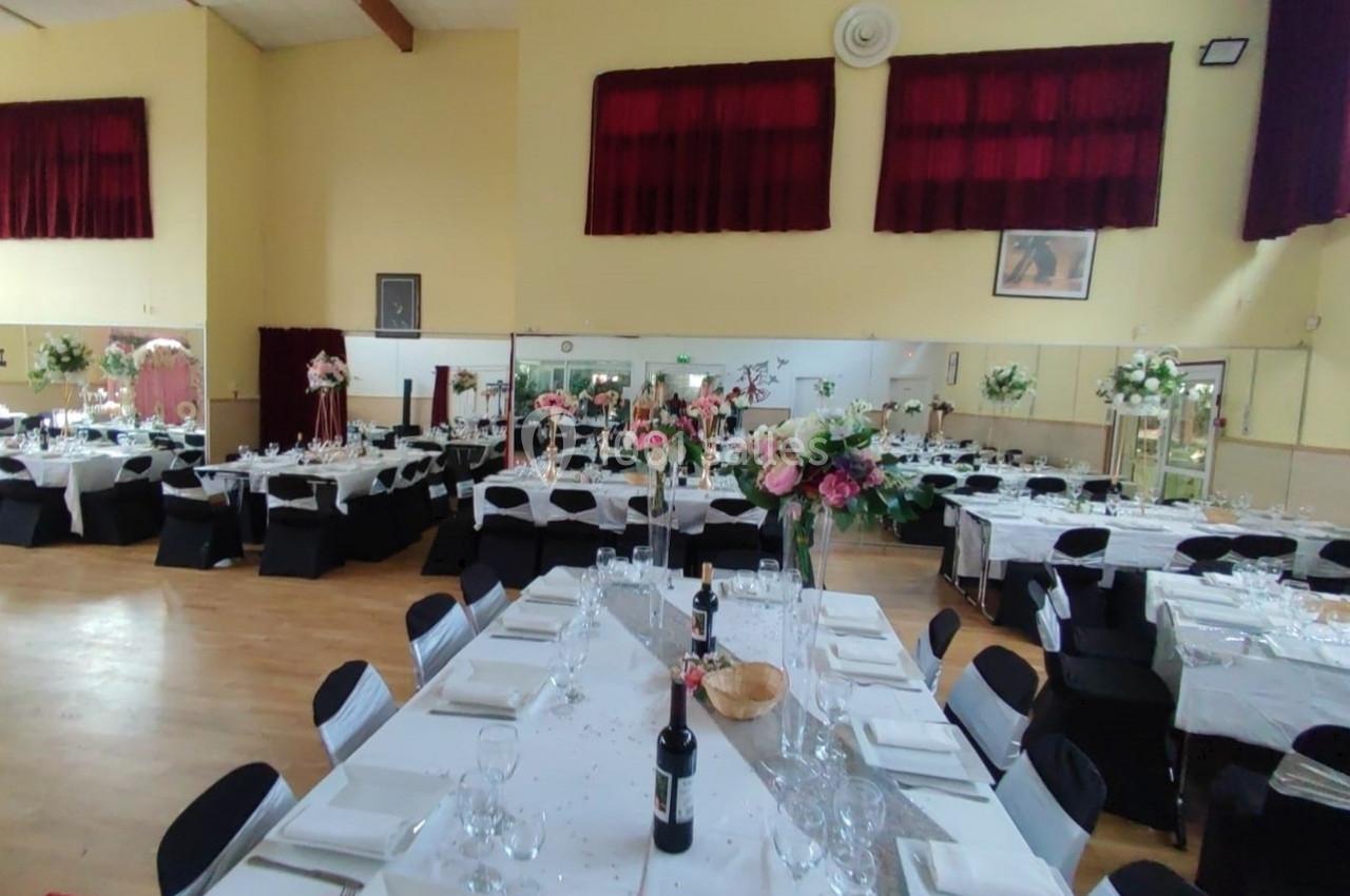 Location salle Nanteuil-lès-Meaux (Seine-et-Marne) - Centre D #4 Salle de réception décorée avec des tables dressées, nappes blanches, chaises noires et arrangements floraux.