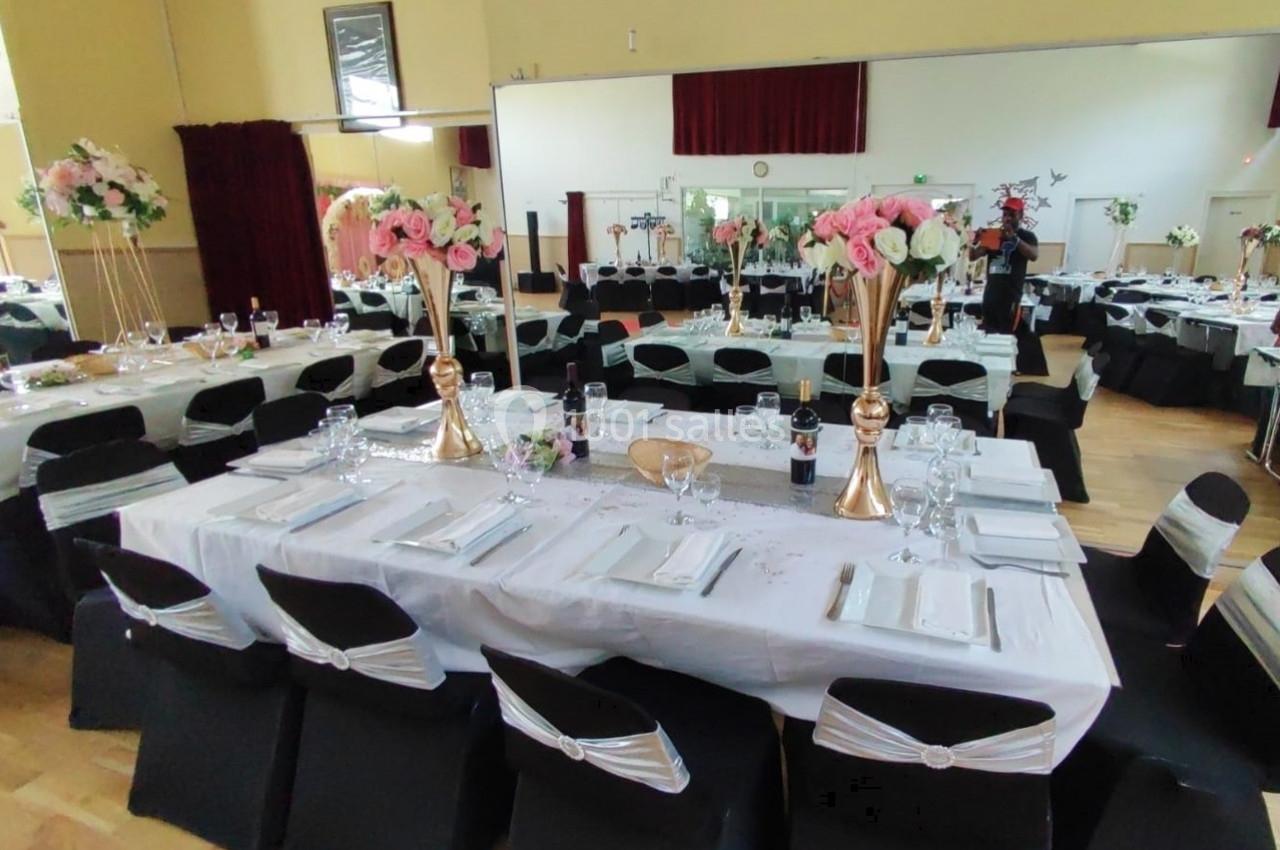 Location salle Nanteuil-lès-Meaux (Seine-et-Marne) - Centre D #3 Salle de réception décorée avec des tables dressées, nappes blanches, chaises noires et arrangements floraux.