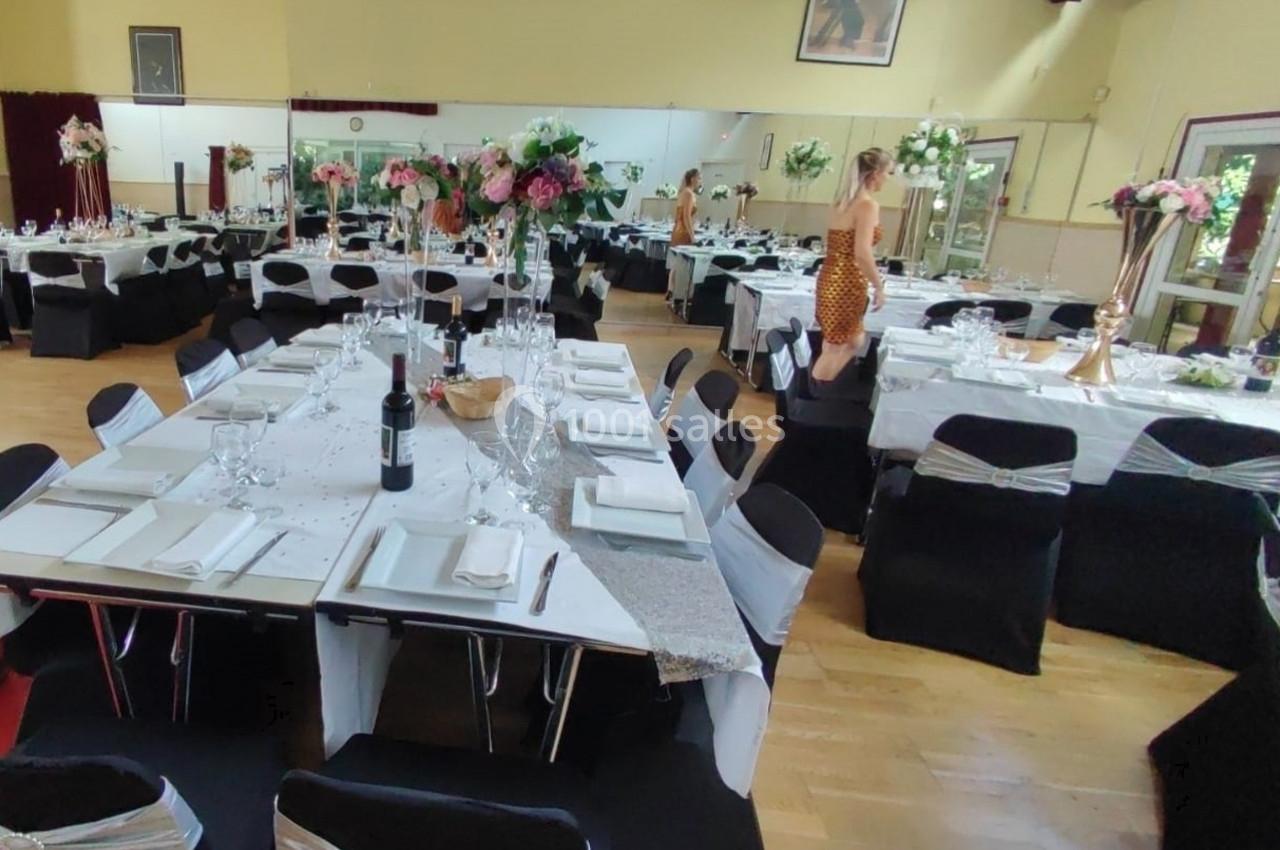Location salle Nanteuil-lès-Meaux (Seine-et-Marne) - Centre D #10 Salle décorée pour un événement avec tables dressées, nappes blanches, chaises noires et arrangements floraux.