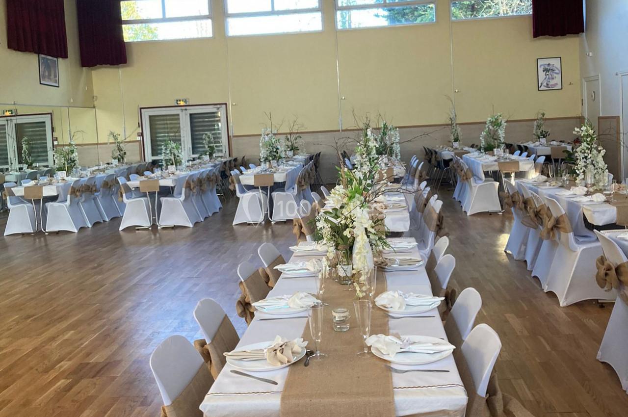 Location salle Nanteuil-lès-Meaux (Seine-et-Marne) - Centre D #12 Salle de réception décorée avec des tables alignées, nappes blanches, chemins de table en toile de jute et bouquets floraux.