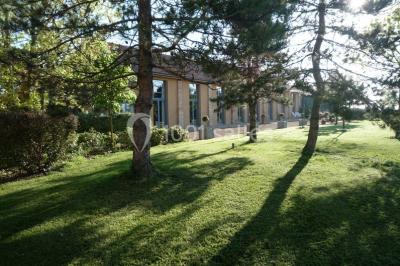 Jardin avec pelouse, arbres et pot en terre cuite au premier plan, éclairé par une lumière douce en fin de journée.