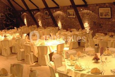 Table dressée avec nappes jaunes, seaux à champagne et verres, sous un grand parasol rouge devant un bâtiment en pierre.