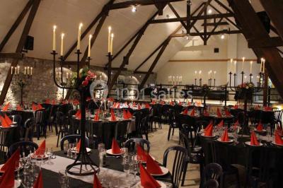Table dressée avec nappes jaunes, seaux à champagne et verres, sous un grand parasol rouge devant un bâtiment en pierre.