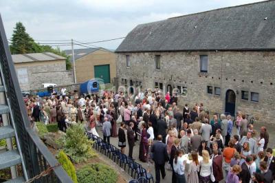 Table dressée avec nappes jaunes, seaux à champagne et verres, sous un grand parasol rouge devant un bâtiment en pierre.