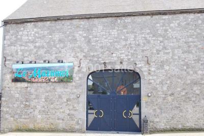 Table dressée avec nappes jaunes, seaux à champagne et verres, sous un grand parasol rouge devant un bâtiment en pierre.