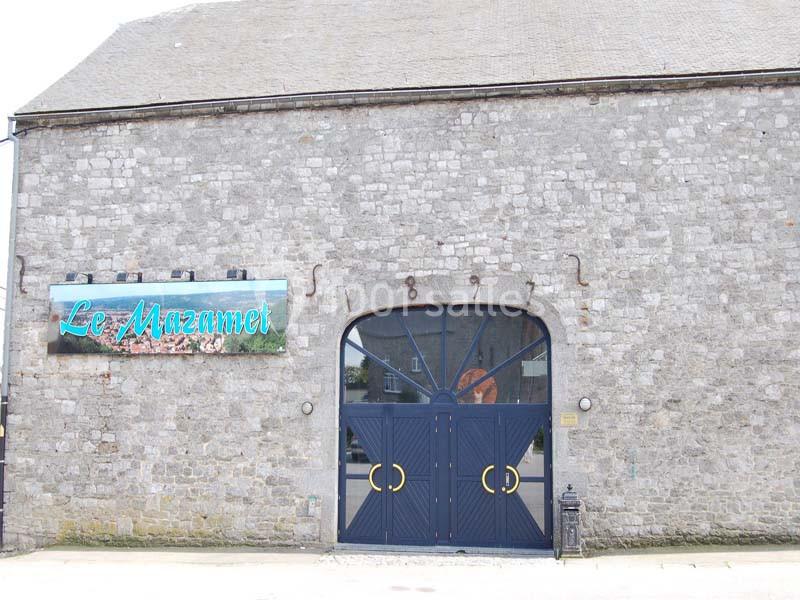 Façade en pierre d'un bâtiment avec une grande porte bleue et une enseigne indiquant ’Le Mazamet’.