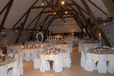 Table dressée avec nappes jaunes, seaux à champagne et verres, sous un grand parasol rouge devant un bâtiment en pierre.
