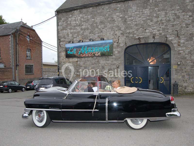 Voiture ancienne décapotable noire stationnée devant un bâtiment en pierre avec une enseigne ’Le Mazamet’.