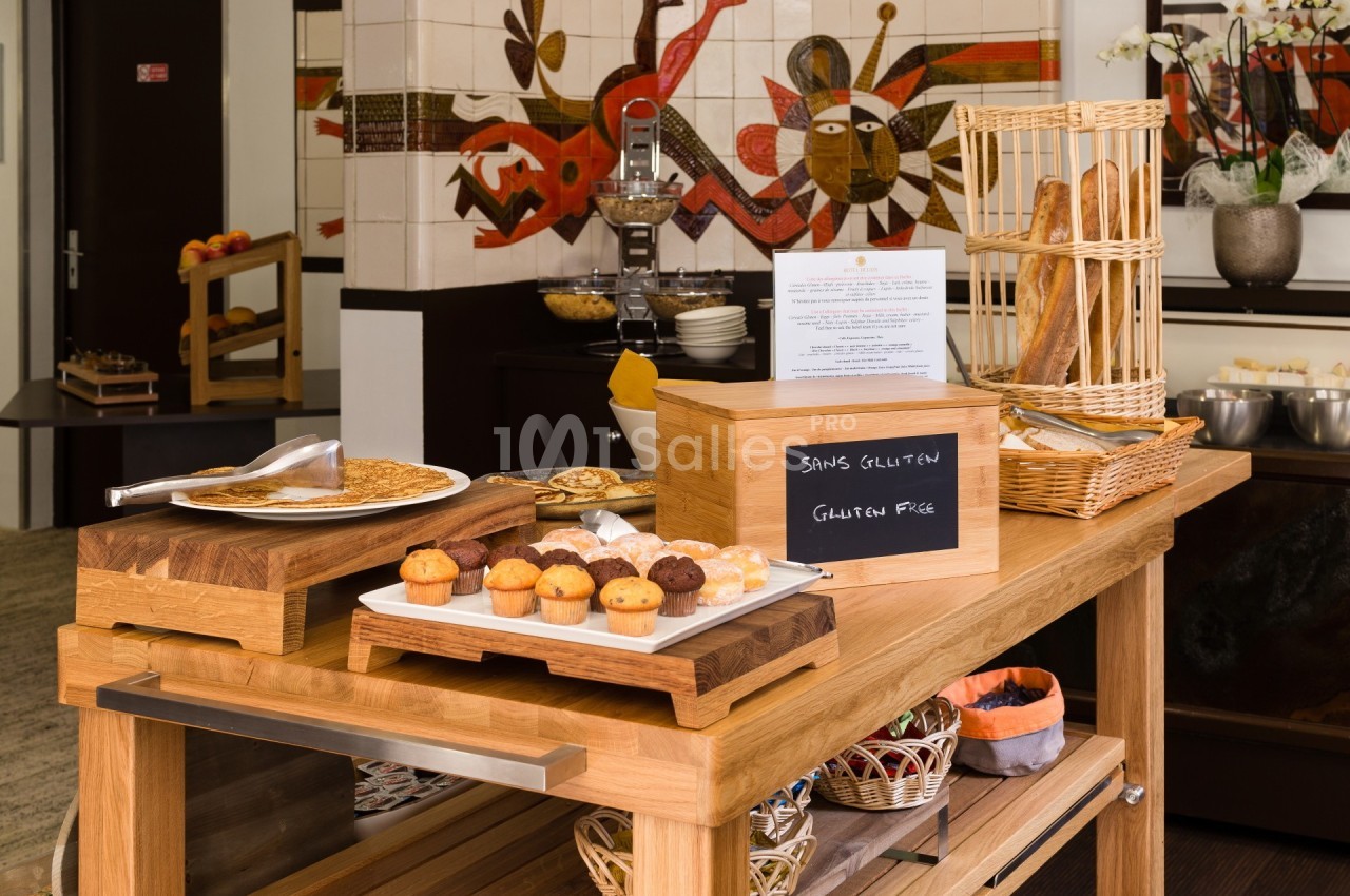 Buffet avec options sans gluten, comprenant crêpes, muffins et pains, présenté sur une table en bois.