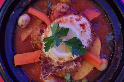 Assiette garnie de légumes variés, morceaux de viande et sauce rouge au centre, présentée sur un lit de salade.