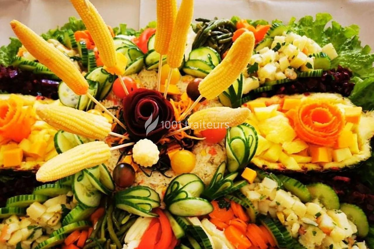Plateau décoratif de crudités avec légumes sculptés, épis de maïs miniatures, et garnitures colorées sur lit de salade.