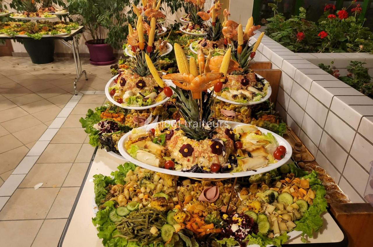 Plateaux garnis de légumes, fruits, salades et décorations comestibles disposés de manière artistique sur une table.