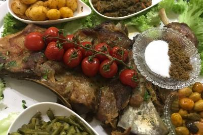 Assiette garnie de légumes variés, morceaux de viande et sauce rouge au centre, présentée sur un lit de salade.