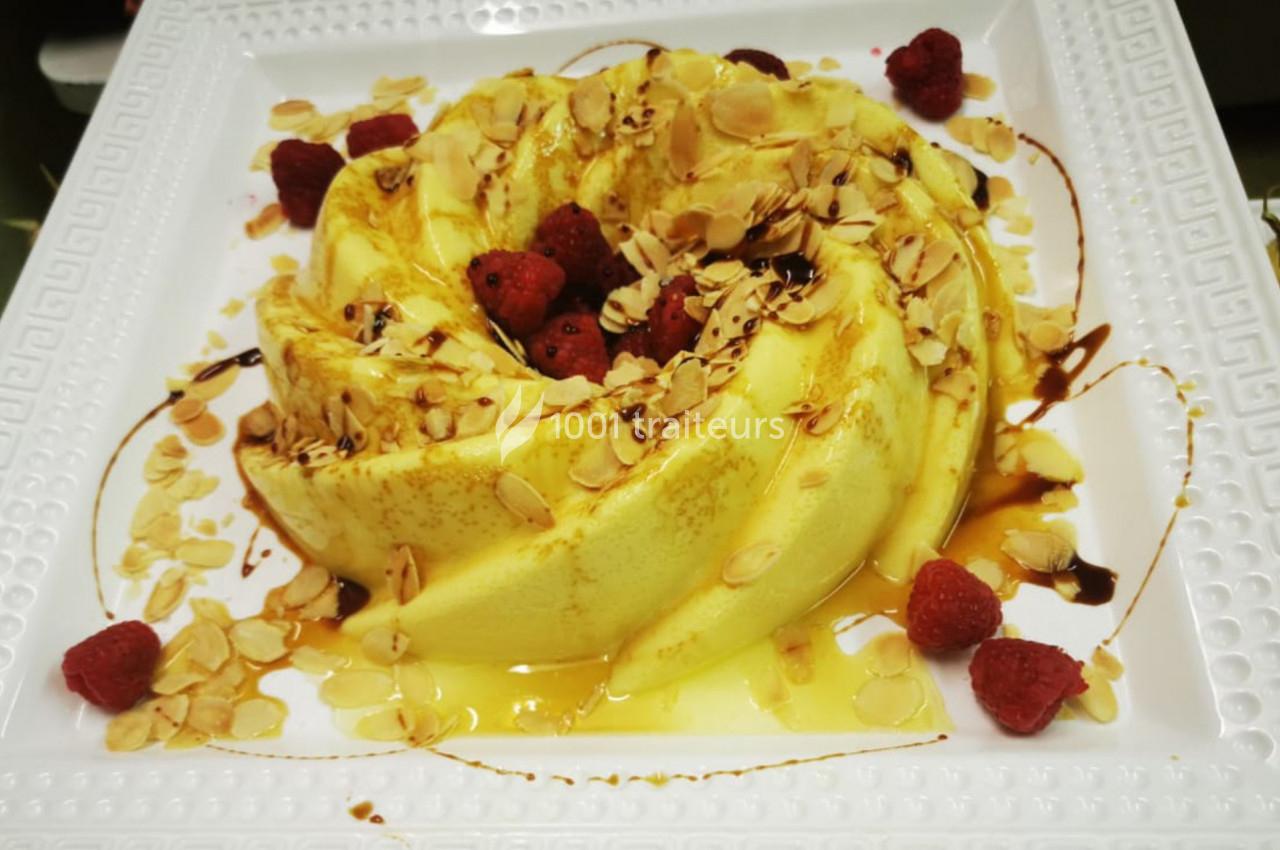Gâteau en forme de couronne, garni de framboises, amandes effilées et filet de caramel sur une assiette blanche.