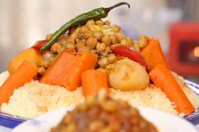 Assiette garnie de légumes variés, morceaux de viande et sauce rouge au centre, présentée sur un lit de salade.