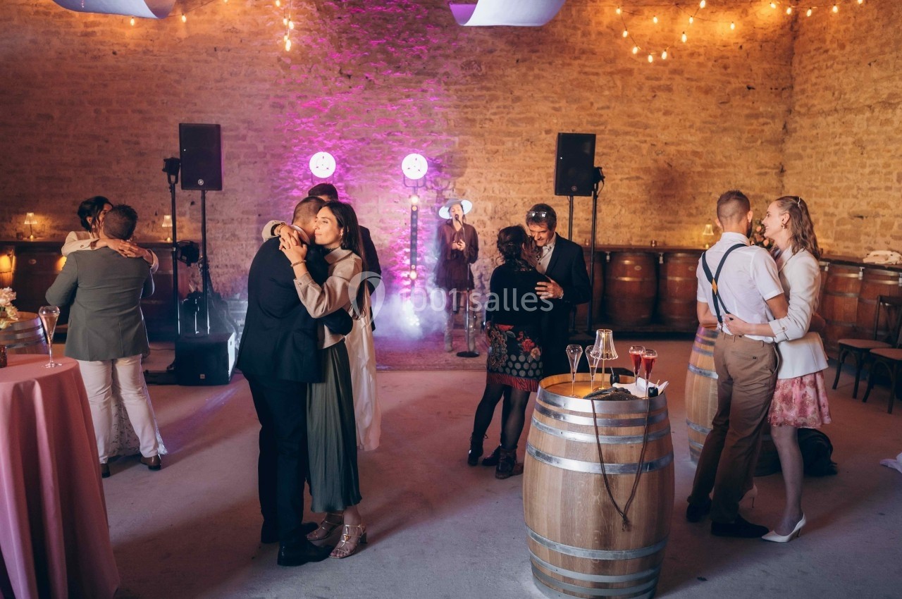 Des couples dansent dans une salle en pierre éclairée par des guirlandes lumineuses et des projecteurs colorés.