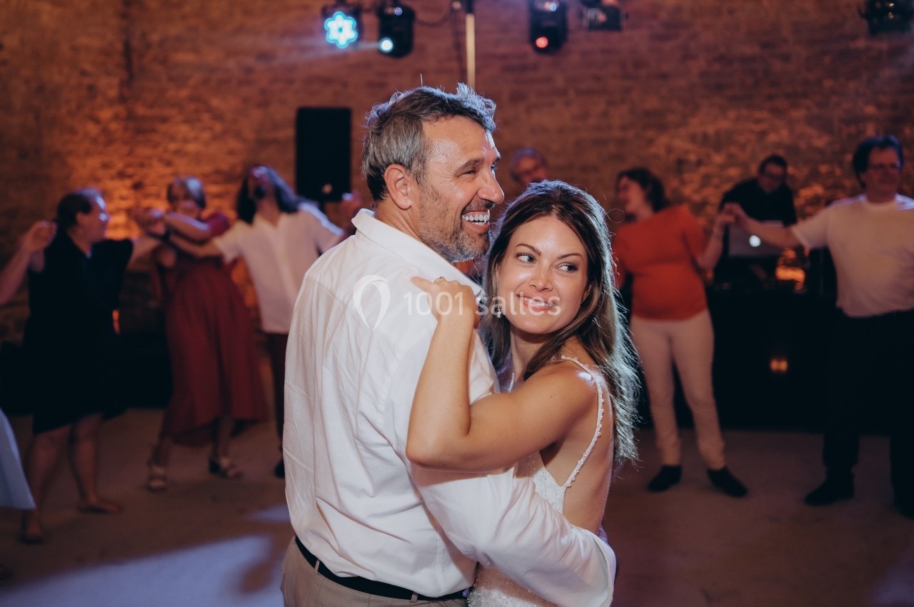 Un couple danse ensemble lors d'une fête, entouré de personnes en arrière-plan dans une ambiance festive.