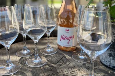Miniature Location salle Artigues (Var) - Domaine de la Mongestine #46 Bouteille de vin rosé entourée de verres vides sur une table en bois, avec une plante en arrière-plan.