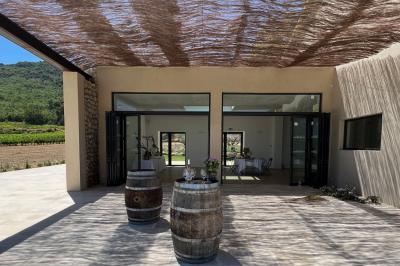 Miniature Location salle Artigues (Var) - Domaine de la Mongestine #7 Bouteille de vin rosé entourée de verres vides sur une table en bois, avec une plante en arrière-plan.