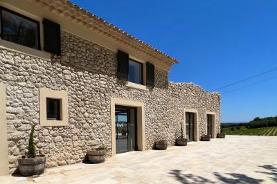 Miniature Location salle Artigues (Var) - Domaine de la Mongestine #28 Bouteille de vin rosé entourée de verres vides sur une table en bois, avec une plante en arrière-plan.