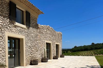 Miniature Location salle Artigues (Var) - Domaine de la Mongestine #27 Bouteille de vin rosé entourée de verres vides sur une table en bois, avec une plante en arrière-plan.