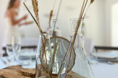 Miniature Location salle Artigues (Var) - Domaine de la Mongestine #35 Bouteille de vin rosé entourée de verres vides sur une table en bois, avec une plante en arrière-plan.