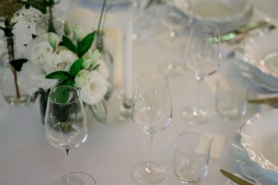 Main d'une personne tenant légèrement une robe blanche, avec un bracelet fin et une bague visible.