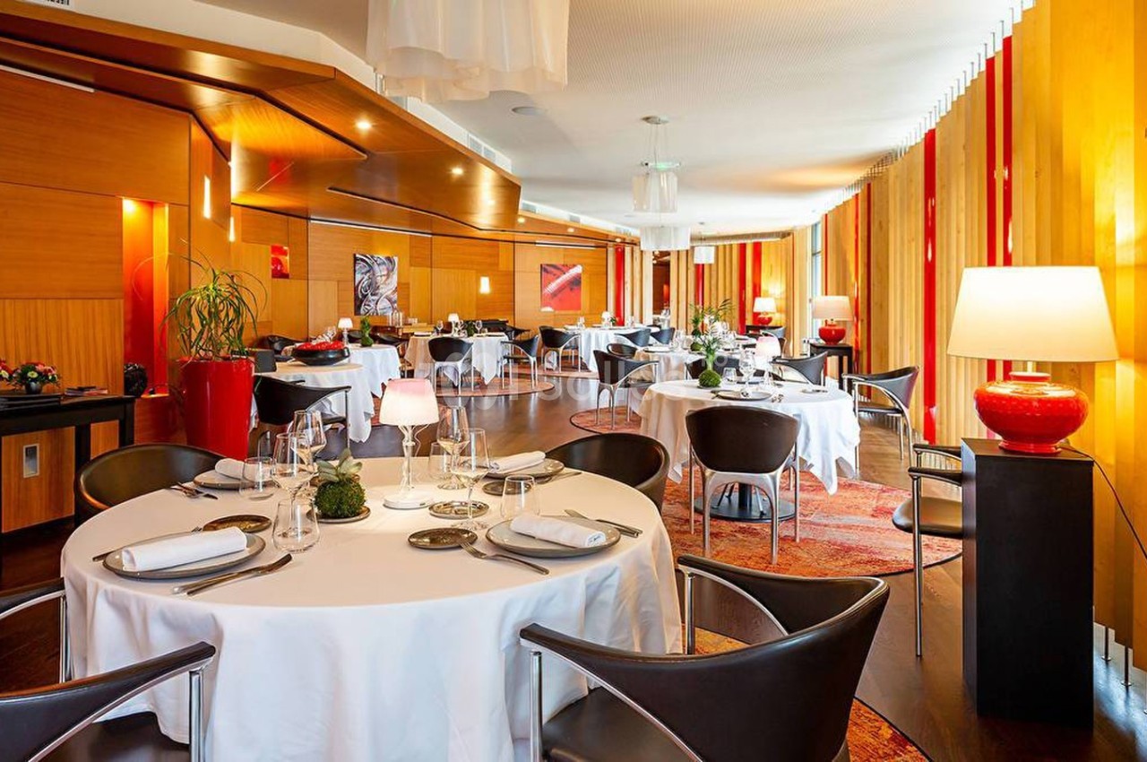 Salle de restaurant élégante avec tables dressées, chaises modernes, éclairage chaleureux et décoration raffinée.