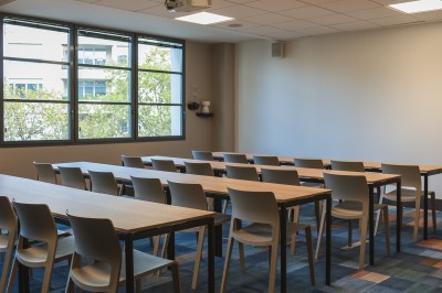 Salle de conférence moderne avec des rangées de sièges orange et un projecteur suspendu au plafond.
