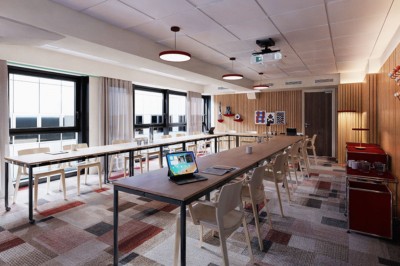 Salle de conférence moderne avec des rangées de sièges orange et un projecteur suspendu au plafond.