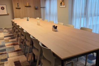 Salle de conférence moderne avec des rangées de sièges orange et un projecteur suspendu au plafond.