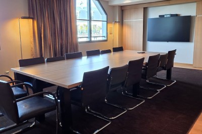 Salle de conférence moderne avec des rangées de sièges orange et un projecteur suspendu au plafond.