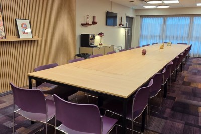 Salle de conférence moderne avec des rangées de sièges orange et un projecteur suspendu au plafond.