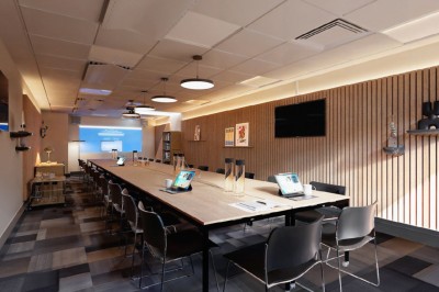 Salle de conférence moderne avec des rangées de sièges orange et un projecteur suspendu au plafond.