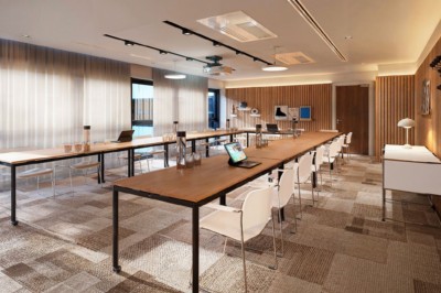 Salle de conférence moderne avec des rangées de sièges orange et un projecteur suspendu au plafond.