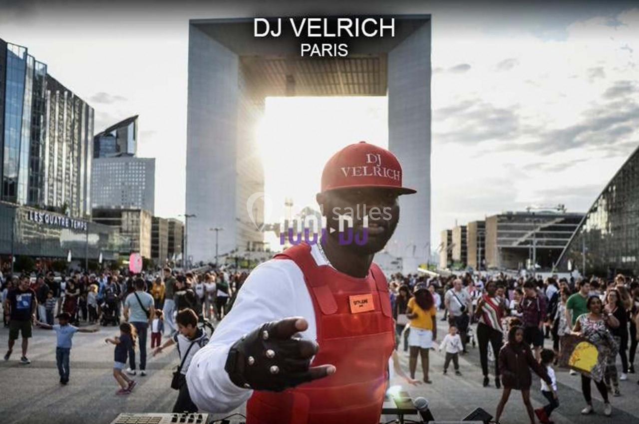 Un DJ mixe en plein air devant une foule rassemblée près de la Grande Arche de La Défense à Paris.