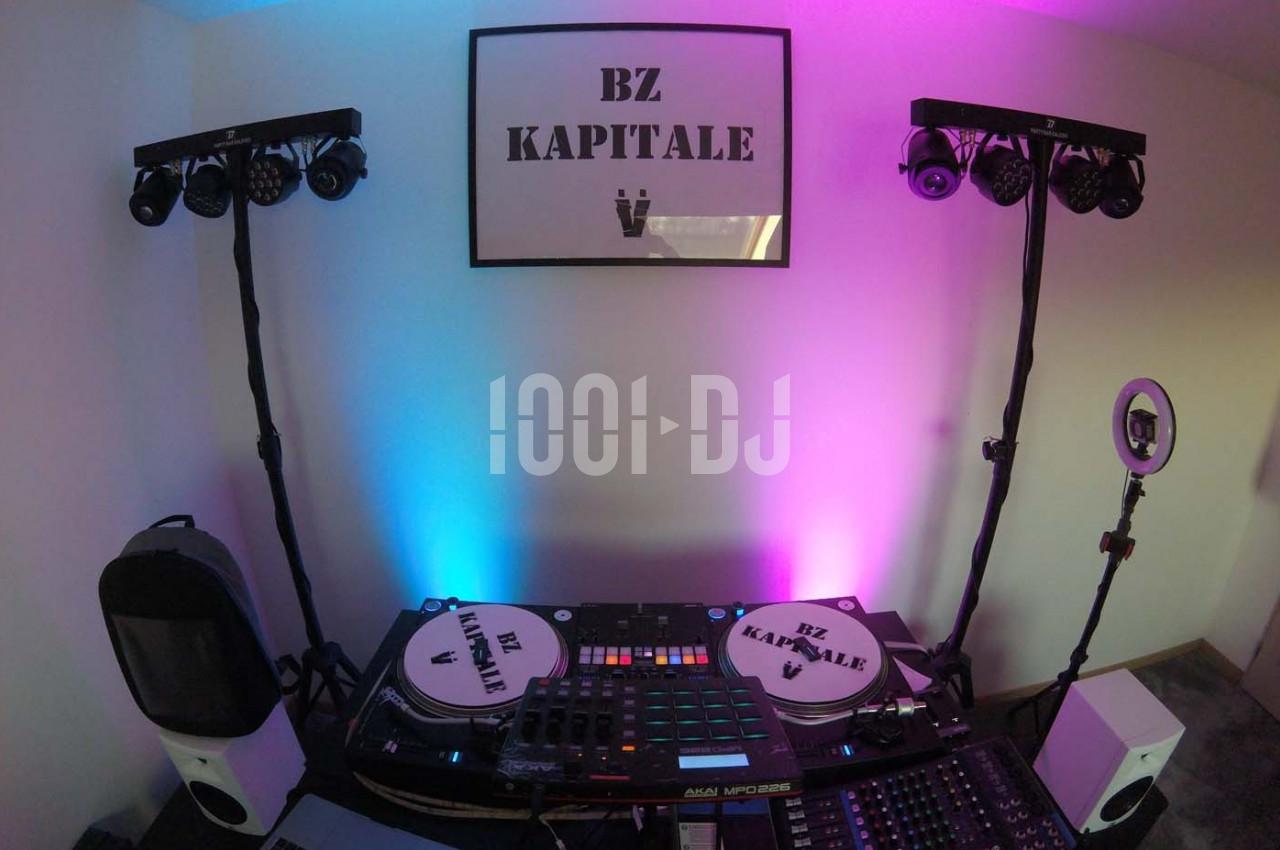 Équipement de DJ avec platines, table de mixage et éclairages colorés dans une pièce décorée.