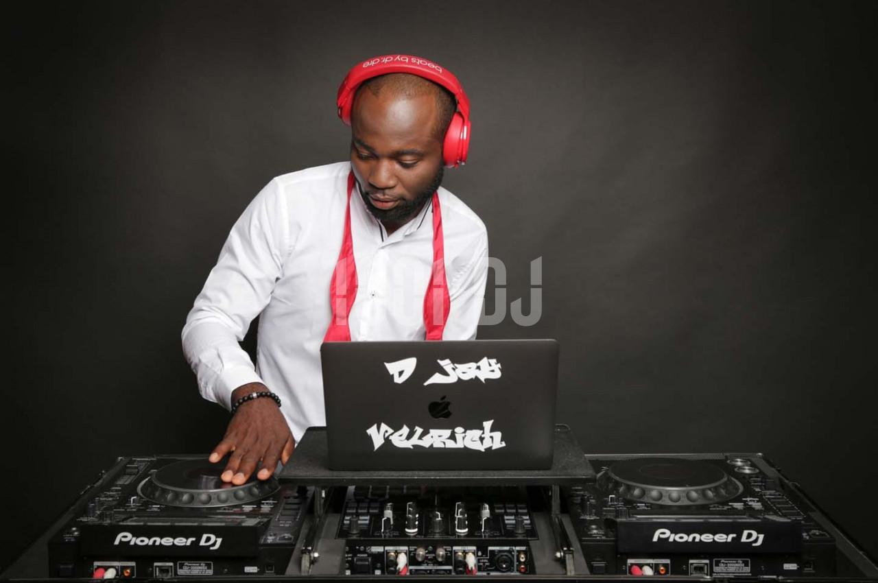 Un DJ portant un casque rouge mixe de la musique sur une table de mixage avec un ordinateur portable.