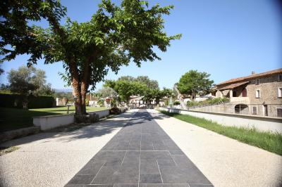 Allée centrale bordée de chaises blanches menant à une arche décorée de fleurs, dans un cadre extérieur arboré.