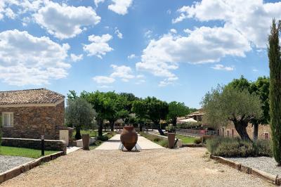 Allée centrale bordée de chaises blanches menant à une arche décorée de fleurs, dans un cadre extérieur arboré.