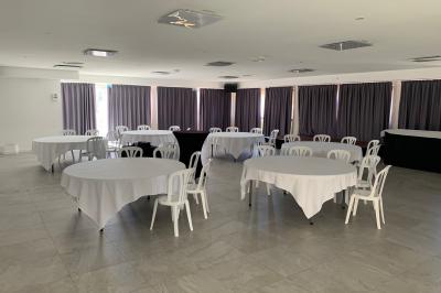 Allée centrale bordée de chaises blanches menant à une arche décorée de fleurs, dans un cadre extérieur arboré.