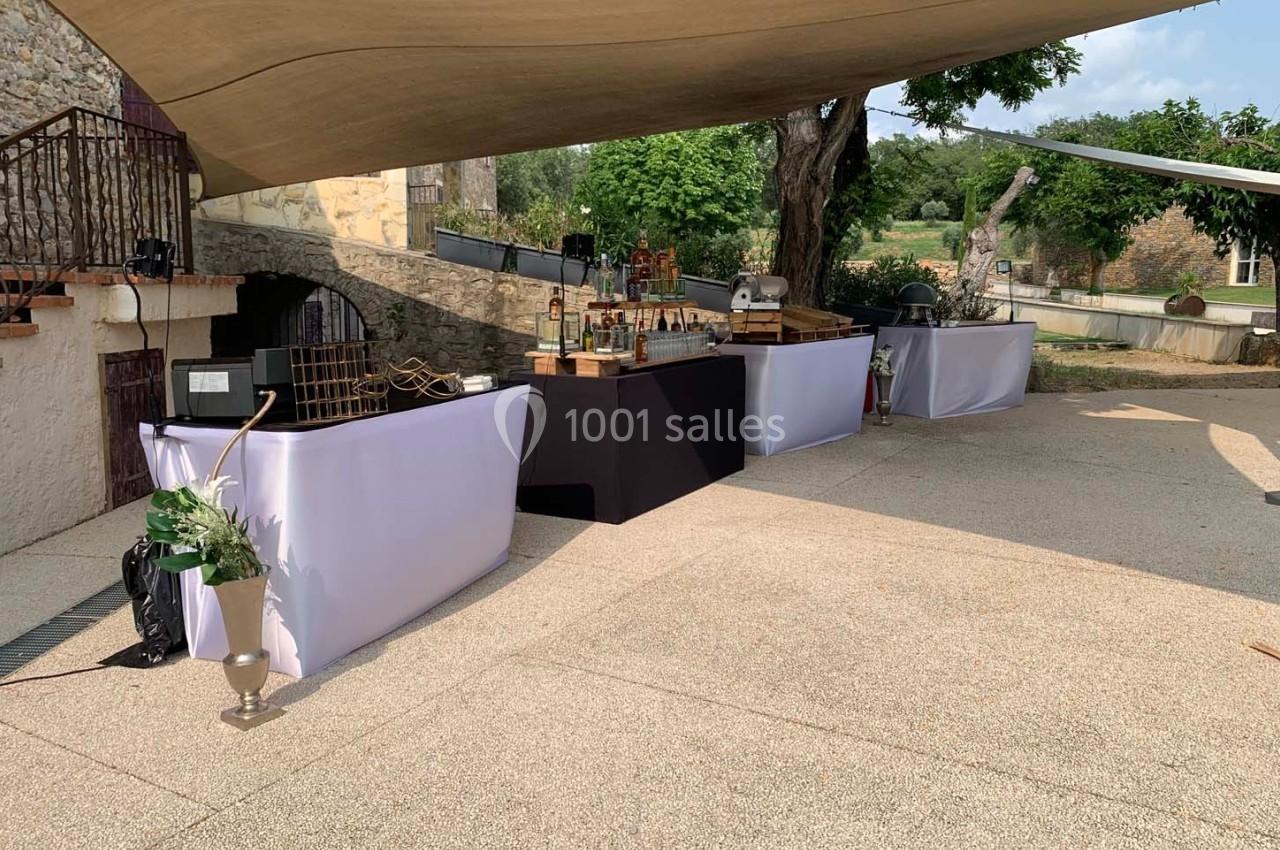 Tables de buffet dressées en extérieur sous une toile tendue, avec un décor champêtre en arrière-plan.